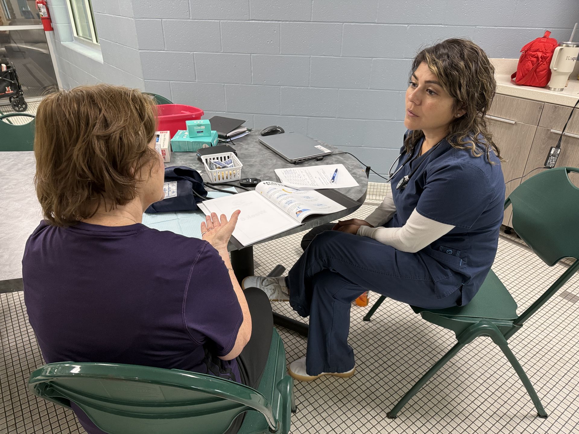 Woman sitting next to a nurse who is taking her blood pressure