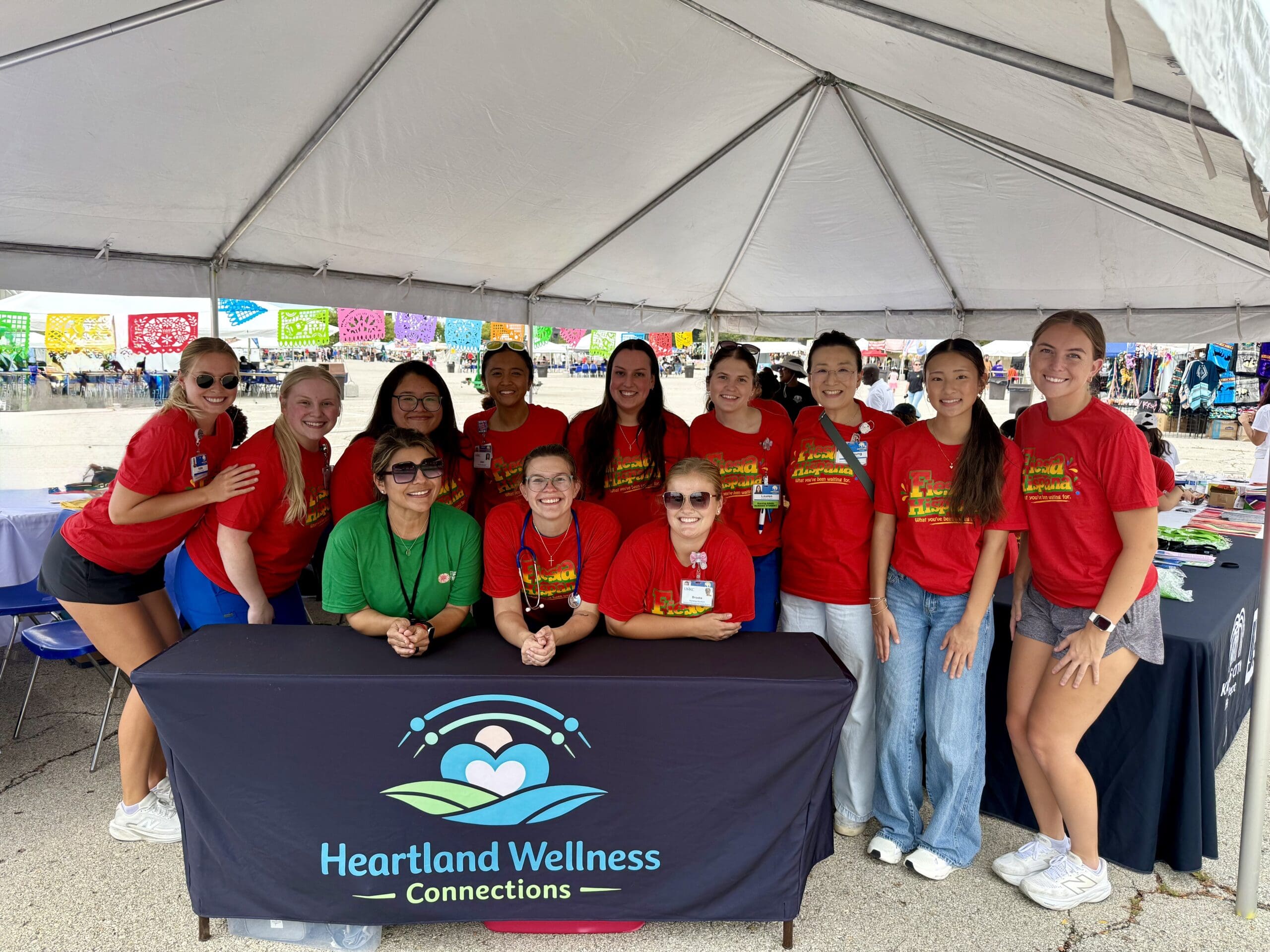 a group of people around a table with the Heartland Wellness Connections logo on the tablecloth
